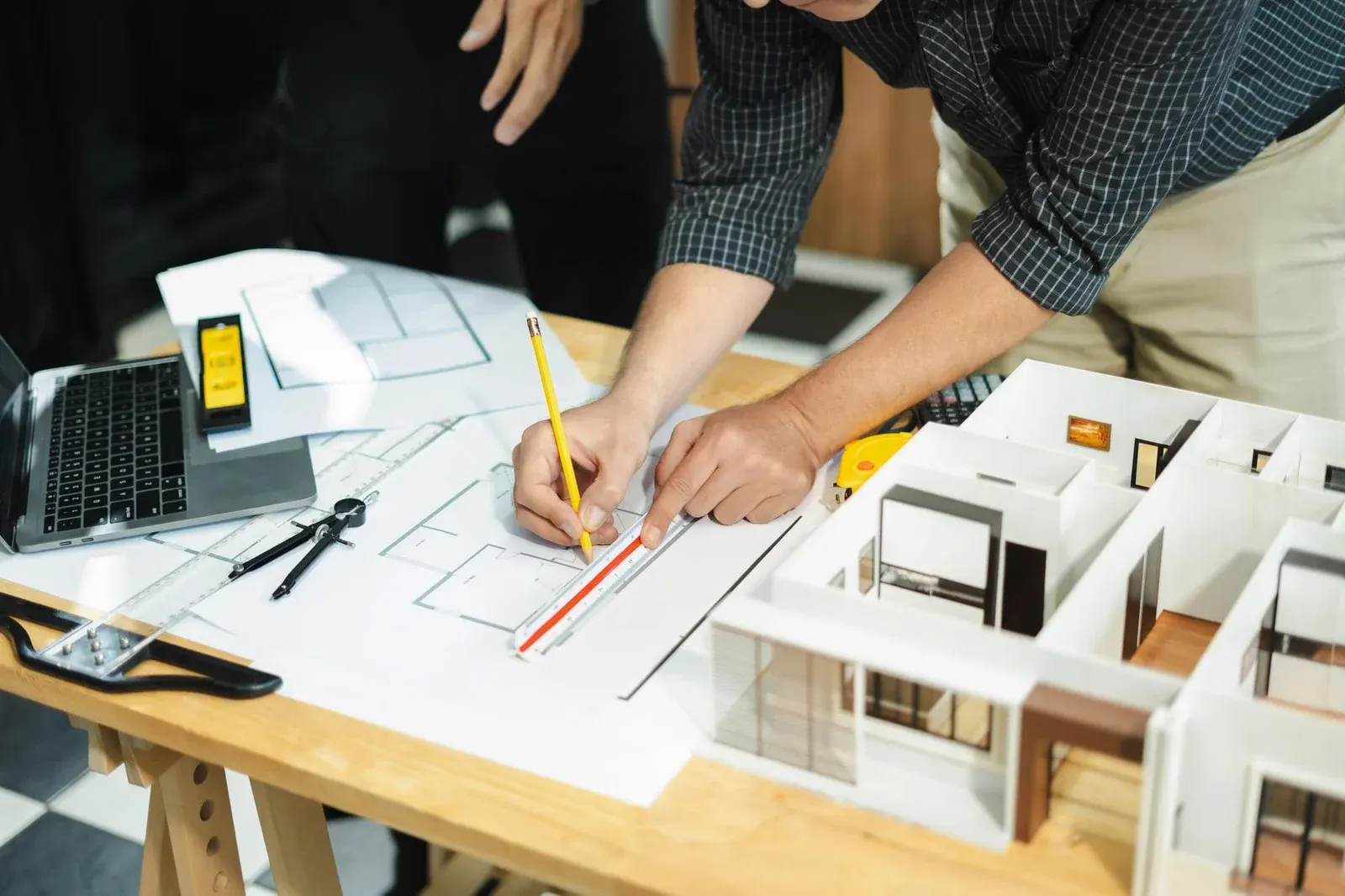 Architect Drawing Floor Plans Beside 3D House Model