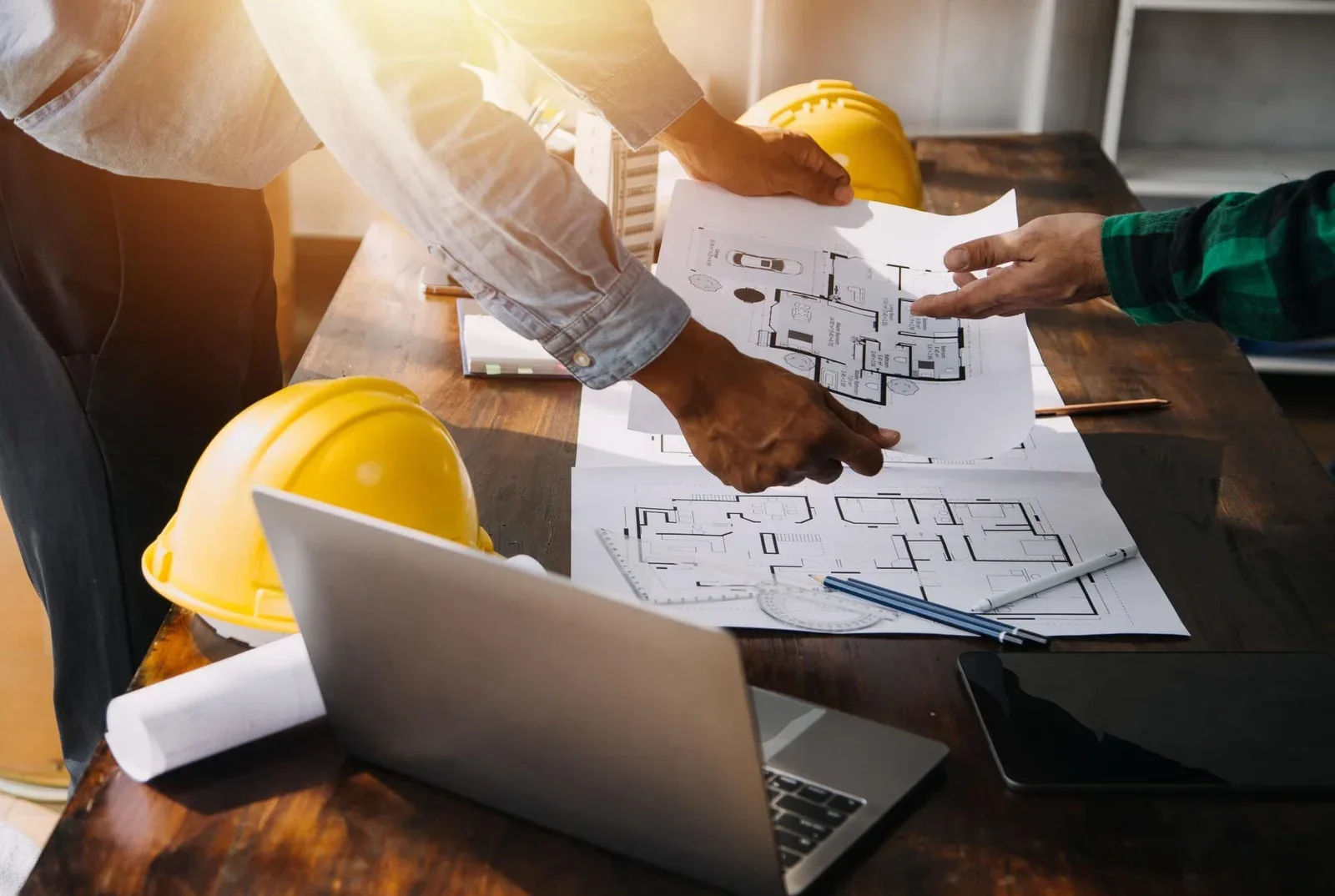 Close-up of project manager with blue hardhat and laptop, demonstrating how to continue monitoring design plans.