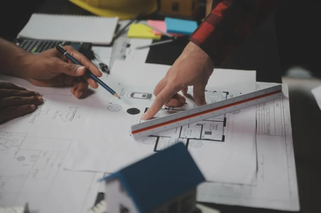 Close-up of engineering team pointing to blueprints with a scale ruler for Epic Construction Management.