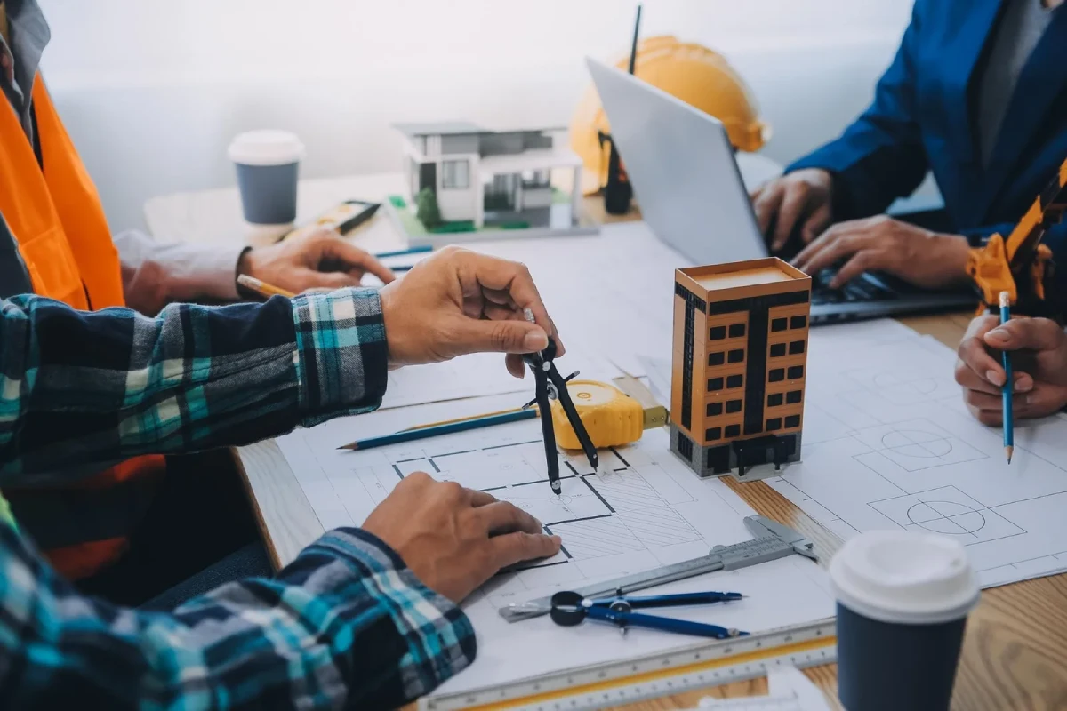 Construction team reviewing blueprints and 3D architectural models during a project coordination meeting with Epic Construction Management.